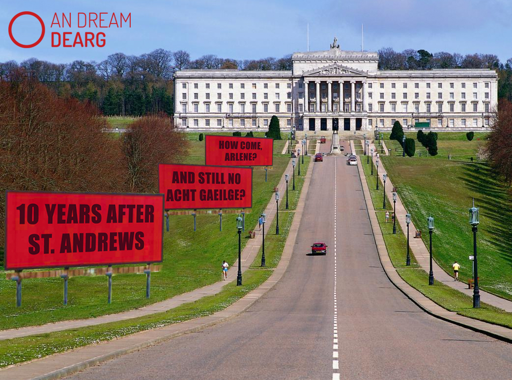 Trí ‘billboard’ lasmuigh de Stormont, Béal Feirste’ –  ’10 years after St. Andrews, still no Acht, how come, Arlene?’