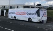 Bus Choláiste Lurgan páirceáilte lasmuigh de Roinn na Gaeltachta mar agóid roimh chuairt Aire Stáit
