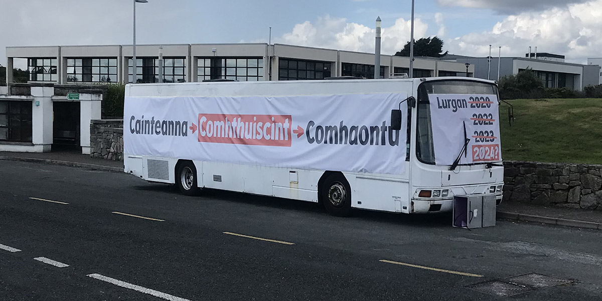 Bus Choláiste Lurgan páirceáilte lasmuigh de Roinn na Gaeltachta mar agóid roimh chuairt Aire Stáit